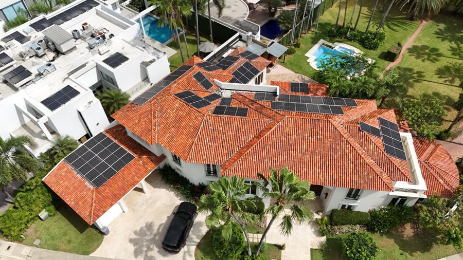 Vista aérea de una casa con su arreglo de paneles y la urbanización alrededor