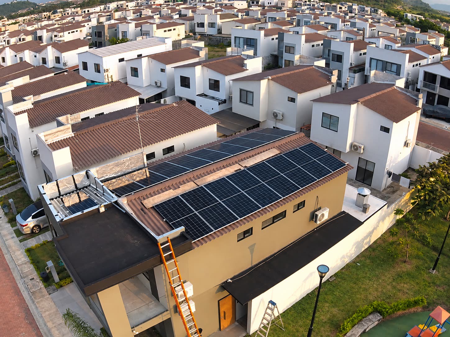 Vista aérea de una casa con su arreglo de paneles y la urbanización alrededor